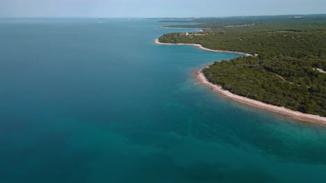 Agua-Clara-Junto-Al-Mar,-Tranquila,-Azul-Y-Turquesa-En-Una-Bahía-De-Playa-Natural-En-Istria,-Croacia-Con-Bosques-Y-Pinos