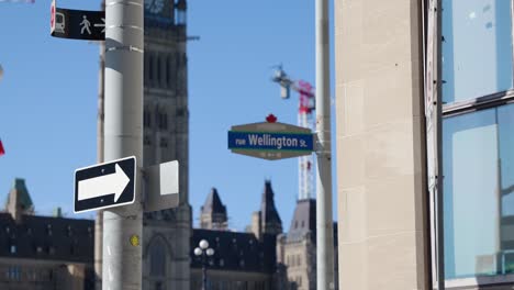 Wellington-Straßenschild-In-Der-Innenstadt-Von-Ottawa-Mit-Dem-Parlament-Von-Kanada-Im-Hintergrund-An-Einem-Sonnigen-Sommertag---4K-Zeitlupe