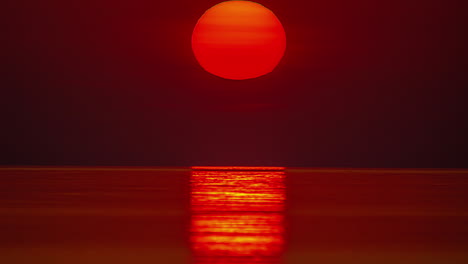 An-amazing-golden-sunset-reflecting-on-the-surface-of-the-ocean---sun-like-a-fiery-ball-in-a-dreamy-time-lapse