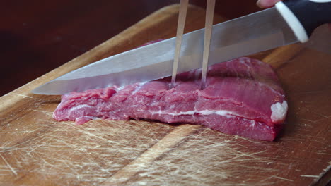 Chopping-raw-beef-steak-meat-carefully-with-skewers