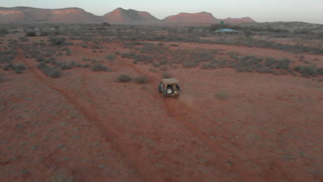 Aerial-rotating-shot-around---above-Jeep-on-dusty-desert-road