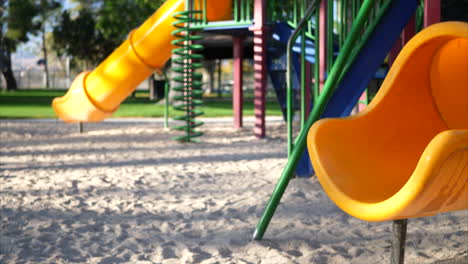 Rutschen-Sie-Rechts-über-Eine-Gelbe-Rutsche-Auf-Einem-Leeren-Kinderspielplatz-Mit-Geräten-Und-Einem-Klettergerüst