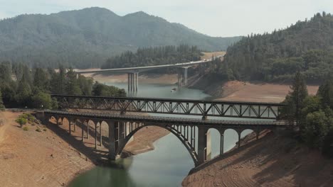 Aerial-view-of-Shasta-Lake-rising-shot-of-train-tracks-and-bridges-in-Northern-California-low-water-levels-during-drought
