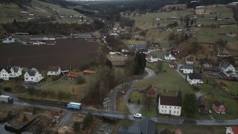 Aerial-shot-of-Cars-passing-small-bridge-over-stream-in-Utvik-village,-Norway