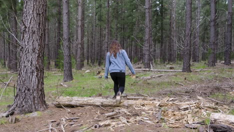Young-girl-walking-between-tall-trees-in-a-forrest