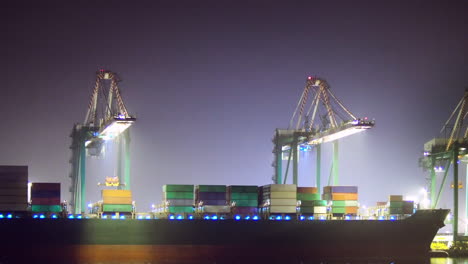 Loading-a-container-ship-at-night,-ZOOM-IN-EASE