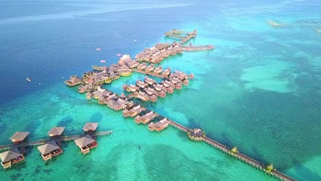 Aerial-flight-over-crystal-clear-water-and-resort-in-Malaysia,-long-distance-shot-moving-forward-in-slow-motion