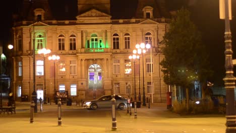 Brightly-lit-colourful-stone-building-in-town-square-at-night