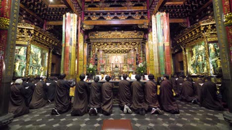 Religious-people-sitting-on-knees-praying-at-Longshan-Temple-in-Taipei,-Taiwan
