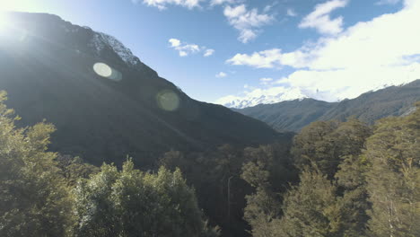 Schwenkaufnahme-Von-Schneebedeckten-Bergen-Und-üppig-Grünen-Wäldern-Und-Tälern-An-Einem-Strahlend-Sonnigen-Tag-In-Neuseeland