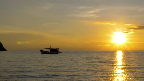 Silhouette-of-a-fishing-boat-on-the-horizon-with-the-sun-setting-in-the-background