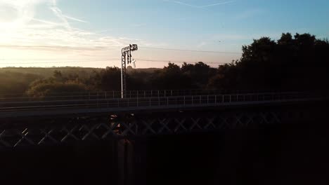 Horizontal-aerial-following---ascending-over-railway-bridge-sunrise,-early,-frosty,-misty-morning