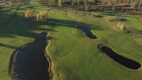 Revealing-a-beautiful-golf-course-from-high-above-with-small-lakes,-bunkers-and-fairways