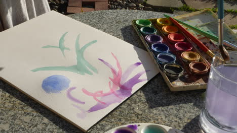 An-artist-painting-with-watercolor-on-a-table-in-an-outdoor-art-studio
