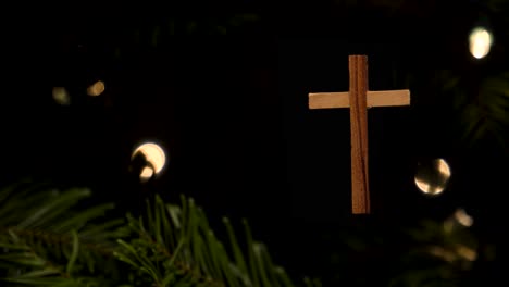 Panning-shot-of-a-simple-wooden-cross-Christmas-tree-ornament-hanging-on-a-tree