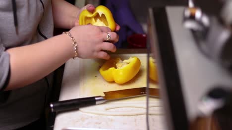 A-side-view-of-cutting-a-yellow-bell-pepper-in-half-on-top-of-kitchen-counter