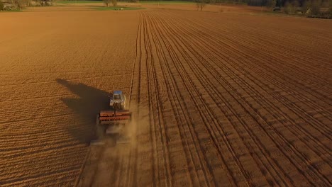 Sowing-fields-with-tractor-and-seeder-in-dusty-field-aerial-view