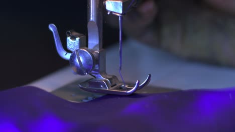 Closeup-of-a-sewing-machine-needle-stitching-a-violet-cloth-with-violet-thread