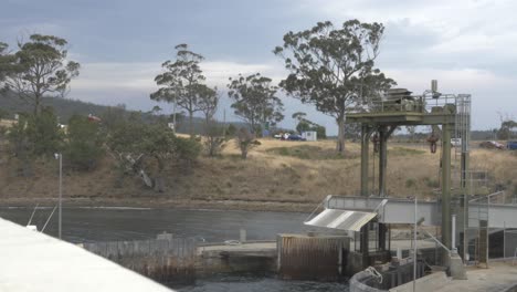Ferry-Boat-Arrives-At-Dock-On-Rural-Island-With-Trees-And-Blue-Sky,-Tasmania,-Australia