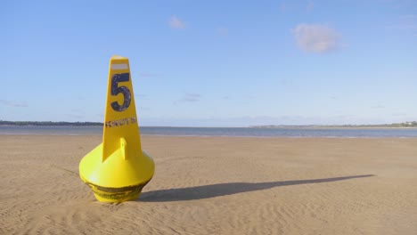 A-speed-limit-buoy-resting-on-sand-at-low-tide
