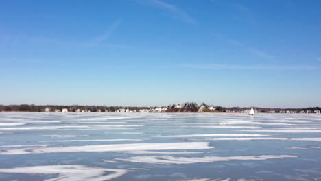 Wide-shot-of-a-wide-frozen-river-with-a-ice-sail-boat-sailing-around
