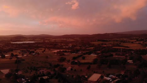 Aerial-shot-of-the-orange-glow-of-sunset-over-farmland-in-rural-Victoria-Australia