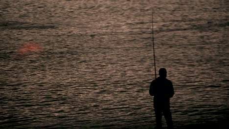 A-man-reeling-in-a-fish-at-dusk-in-New-Zealand