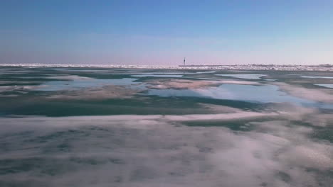 Flugaufnahme-über-Einem-Eisigen,-Zugefrorenen-See,-Um-Einen-Leuchtturm-Auf-Einem-Pier-Zu-Entdecken