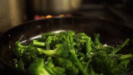 Close-Up---Sprinkling-salt-on-steamed-fresh-green-broccoli-on-a-black-frying-pan