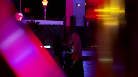 Muslim-women-taking-selfies-around-multicolored-flashing-lights-at-night