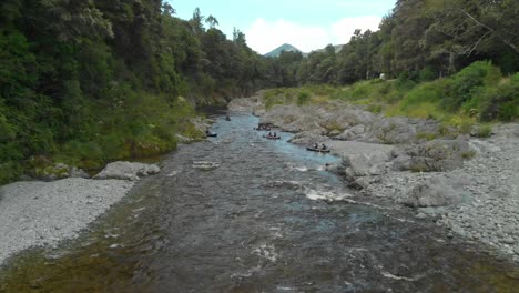 La-Gente-Rema-En-Kayak-Por-El-Rápido-Con-Rocas-En-El-Hermoso-Y-Prístino-Río-Azul-Claro-Pelours,-Nueva-Zelanda---Drone-Aéreo