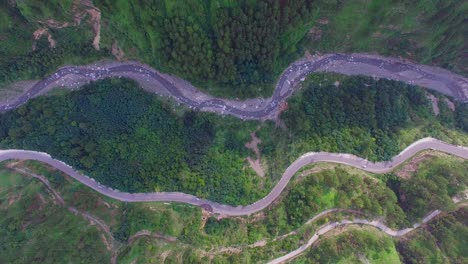 Aerial-flight-over-the-car-driving-along-the-road-surrounded-by-forest,-a-curved-winding-roads-trough-the-forest-with-river,-Top-down-shot-of-traffic-on-roads-through-the-spring-forest