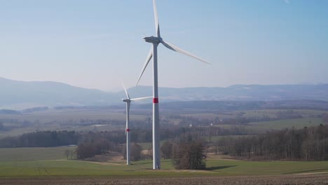 Windmühlenturbinen-Im-Feld-Mit-Hügeln-Im-Hintergrund---Panoramaaufnahme---Zeitlupe