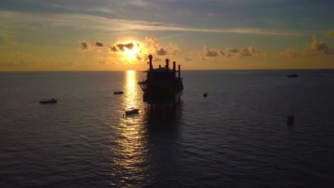 Aerial-flight-at-stunning-sunset-over-ocean-along-an-oil-rig-in-Mabul,-Malaysia