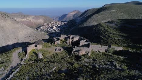 Aerial-orbit-shot-of-the-ruins-of-the-old-customs-building-in-the-Apache-Hill-with-the-Real-de-Catorce-town-in-back,-San-Luis-Potosi,-Mexico