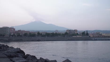 Two-open-water-swimmers-in-the-bay-at-Catania,-Italy-with-Mount-Etna-smoking-in-the-background