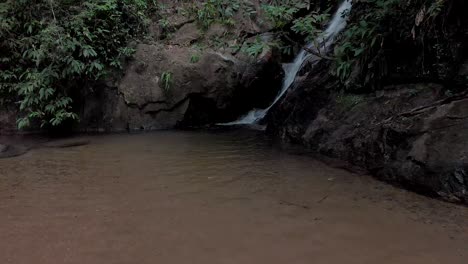 Langsam-Nähern-Wir-Uns-Einem-Kleinen-Wasserfall,-Der-Von-Einer-Sandbank-Aus-In-Einen-Kleinen-Teich-Im-Tropischen-Bergwald-Von-Rio-De-Janeiro-Mündet