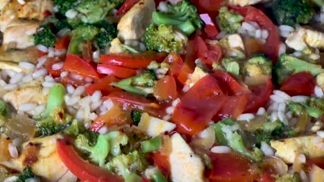 Boiling-water-in-a-pan-with-rice,-tomato,-chicken,-broccoli,-pepper-and-spices