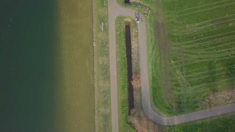 Cycling-on-pathway-beside-the-lake-drone-footage
