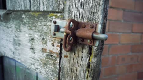 Rusting-old-bolt-lock-on-worn-wooden-door