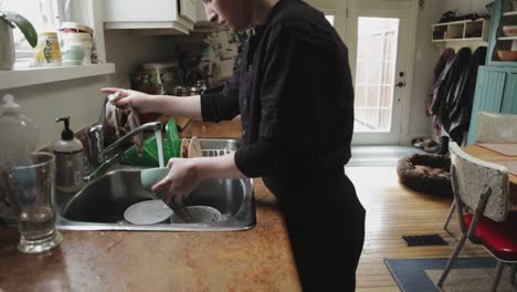 Tilting-shot-of-a-hip-looking-person-doing-dishes