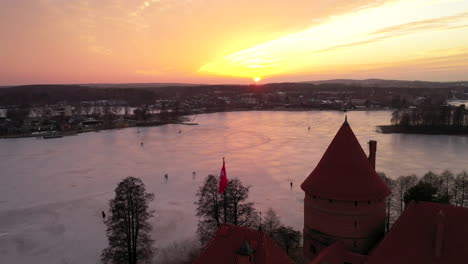 AERIAL:-Flying-Over-the-Gotic-Style-Medieval-Trakai-Island-Castle-with-Lithuanian-Flag-Waving-on-One-of-the-Towers
