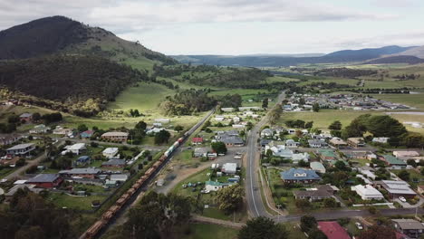 Drone-Shot-Of-Train-Passing-Through-Rural-Green-Country-Town-in-Tasmania,-Australia