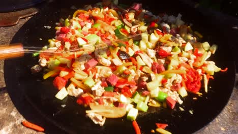 delicious-colorful-wok-with-bacon-fried-in-a-big-pan,-food-being-cooked-outside-in-the-summer,-homemade-outdoor-kitchen