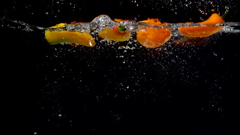 Vibrant-sweet-peppers-being-dropped-into-water-in-slow-motion