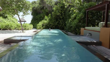 Woman-jumps-into-a-long-rectangular-pool-at-luxury-villa-resort-in-the-Maldives