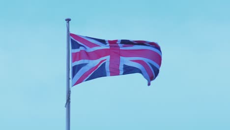 Close-up-of-Union-Jack-Flag-waving-in-the-wind---British-flag-against-light-blue-sky-4K