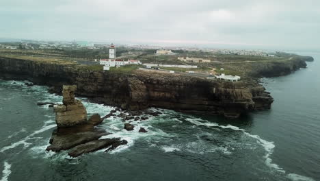 AERIAL---Awesome-drone-footage,-turning-around-lightouse-and-cliffs-at-Cabo-Carvoeiro-in-Peniche,-Portugal