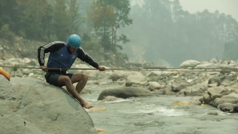 A-trainer-of-a-mountaineering-institute-of-the-Himalayas-crossing-the-mountainous-river-by-rope,-practicing-to-cross-the-river-with-rope