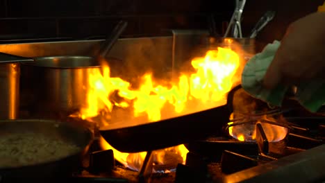 SLOWMO---Chef-in-luxury-restaurant-pouring-oil-and-flame-frying-fish---close-up